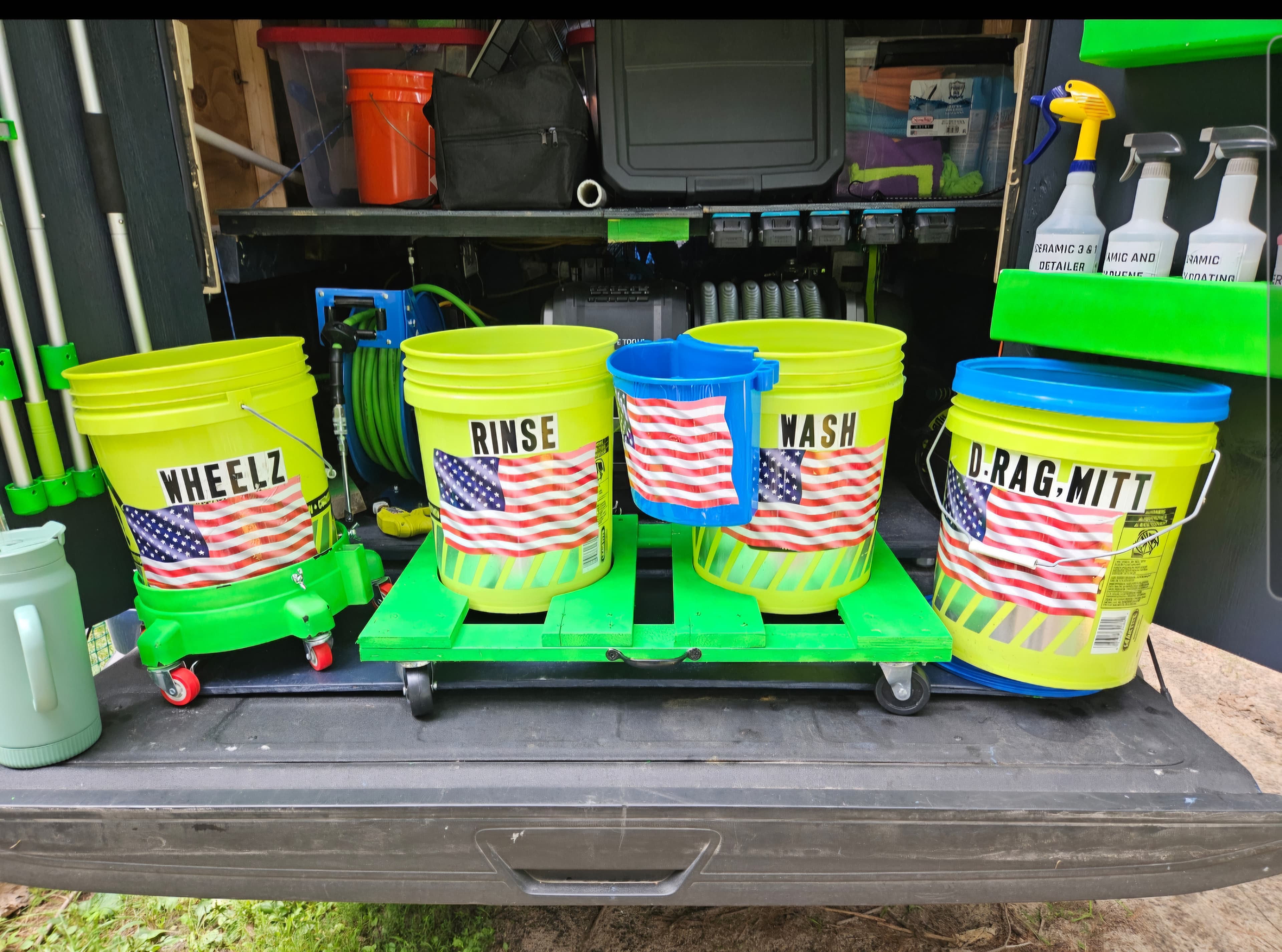 Car detailing setup with labeled yellow buckets and American flag decals on green rolling platforms.