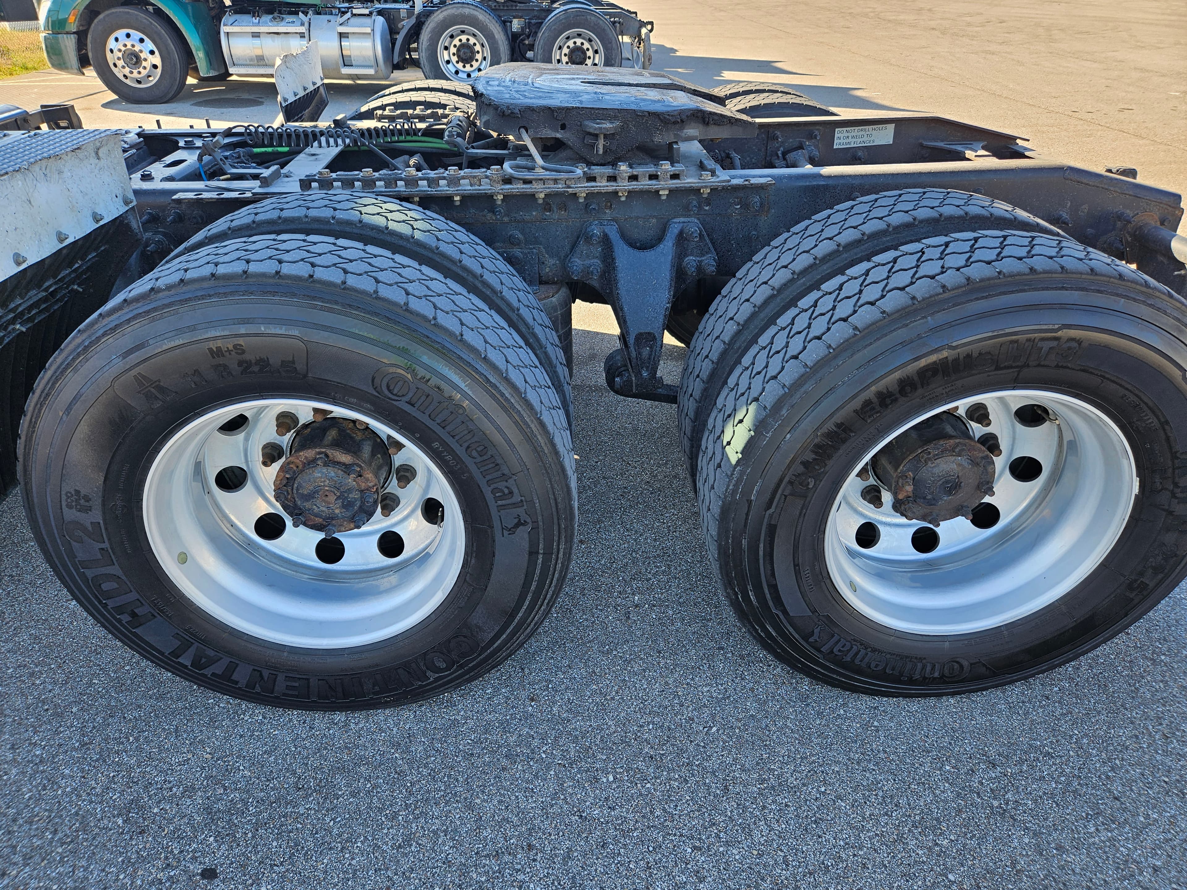 Close-up of the rear dual wheels and fifth wheel coupling on a semi-truck chassis.